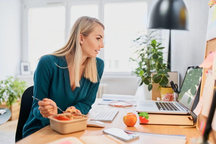 Young woman eating a healthy meal at work after learning about nutrition.