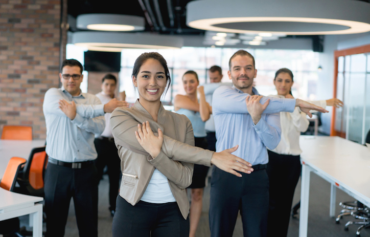 Office workers stretching as part of a workplace health and wellness activity