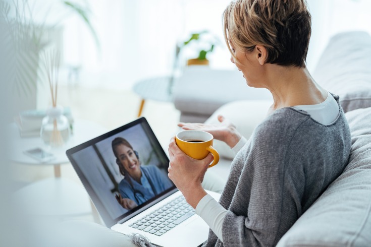 Woman sitting on her couch having a telehealth virtual consultation with her psychologist.