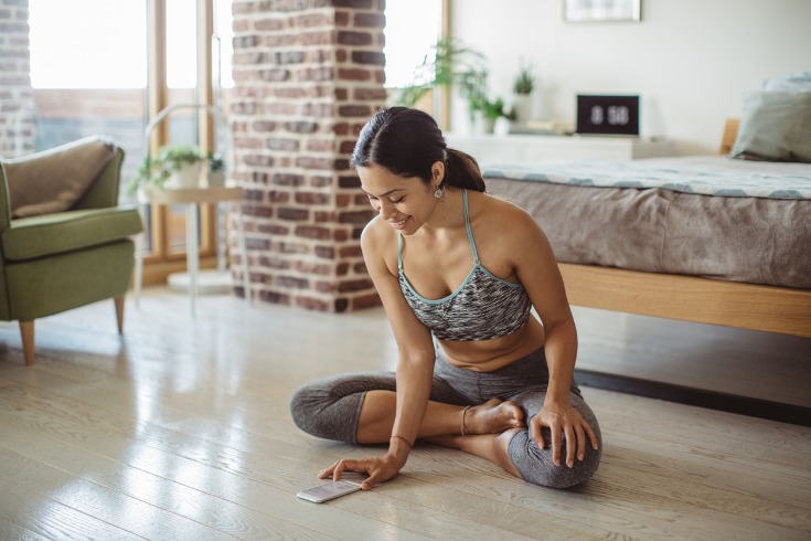 Young women using a fitness app for at home exercise. 