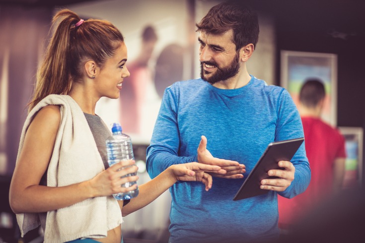  young woman working with a personal trainer on a custom exercise program