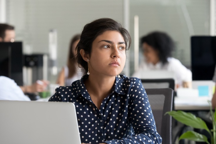 Woman looking into the distance while having feelings of complacency in the workplace.