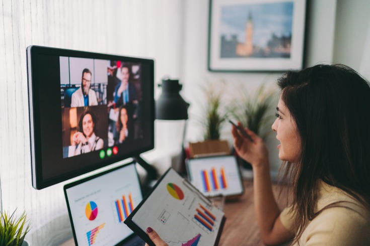 Woman speaking with colleagues about her work from home routine and work-related tasks while on a morning meeting via webcam.