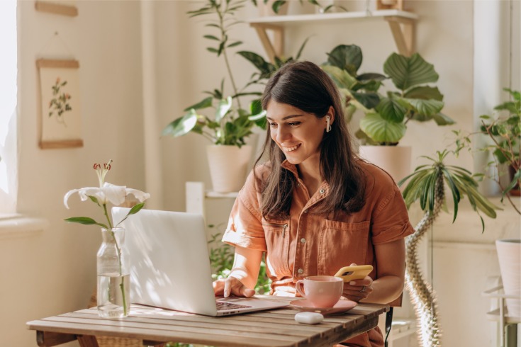 Woman sitting at her table while working from home and keeping to her daily mental health checklist.