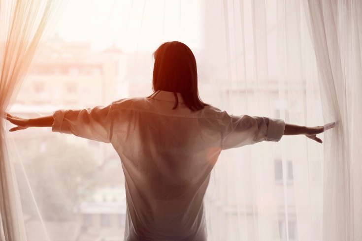  Young woman opening her curtains to start her day off right