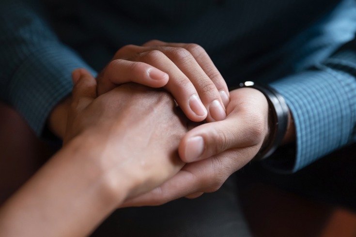 Man holding his partner’s hand in order to comfort and support her through depression.