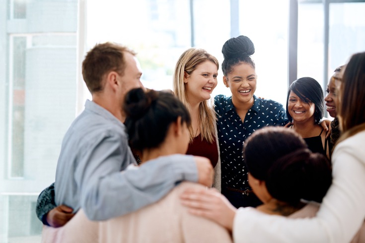 Colleagues sharing a group hug after discussing why trust is important in the workplace.