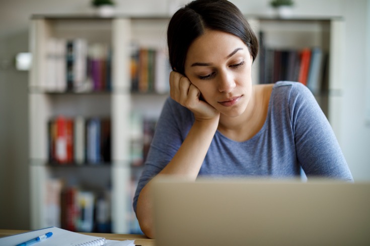 Woman sitting at her desk with no motivation while working from home.