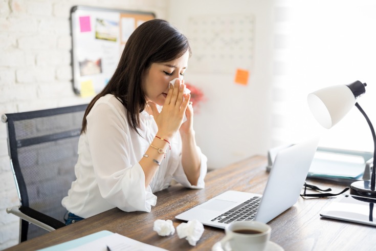 Young female office worker, stuck at work with a virus